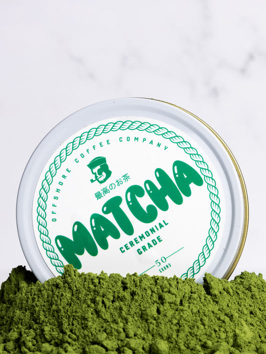 Matcha powder with a container labeled 'Matcha Ceremonial Grade' on a white background